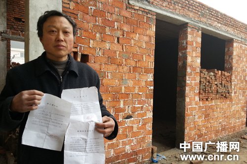已经搭建起来的小屋前,老周拿着收到的《停工通知书》